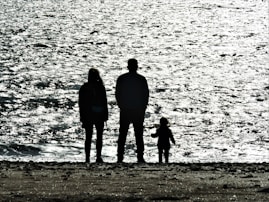 3 men standing on seashore during daytime