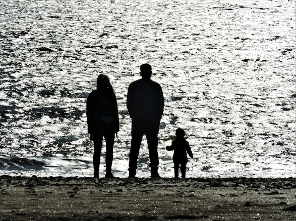 3 men standing on seashore during daytime