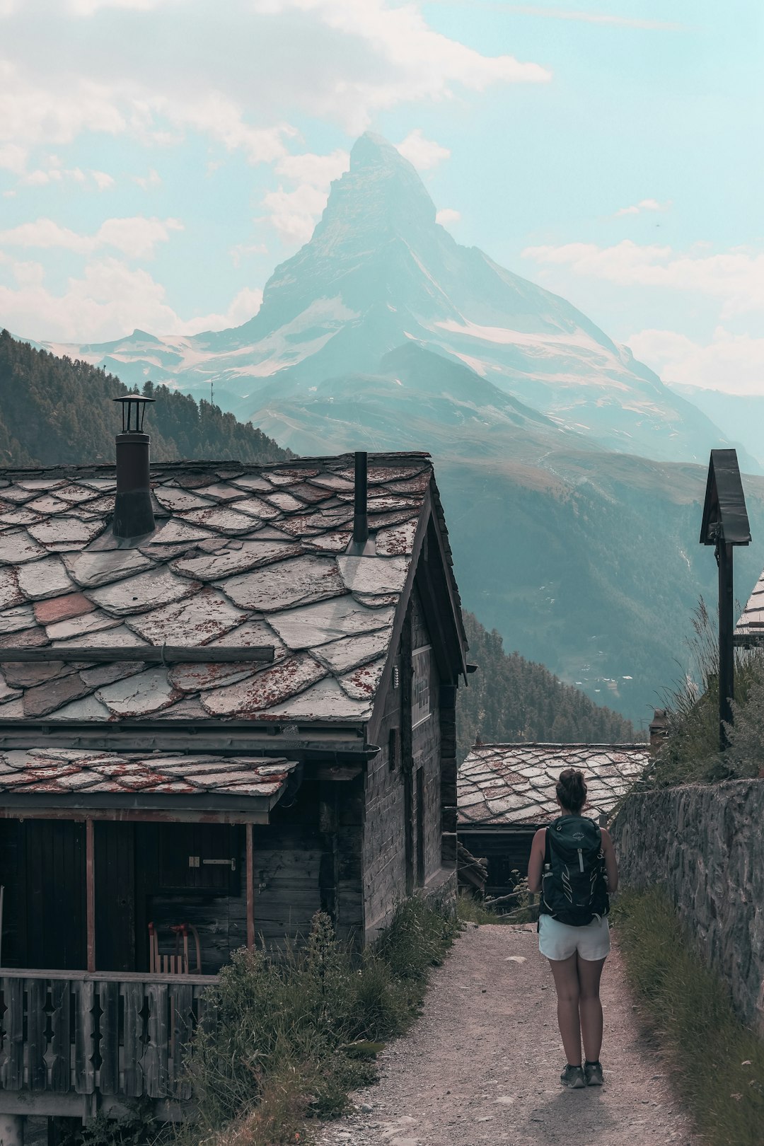 man in red jacket standing near brown wooden house during daytime