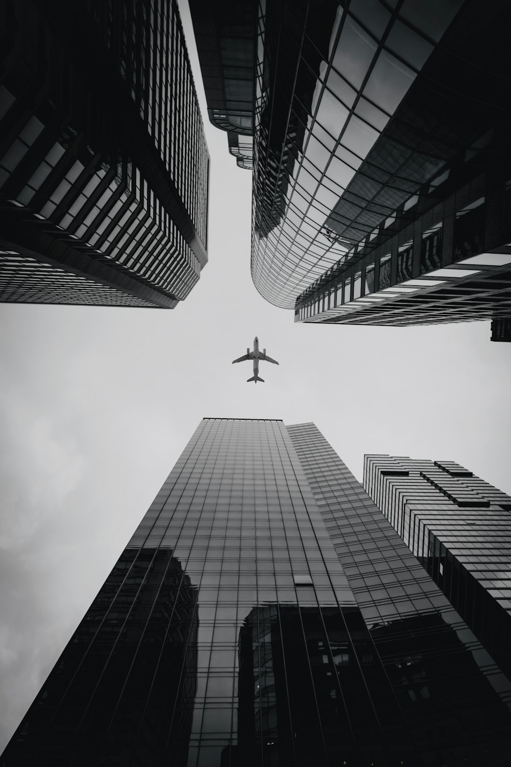 airplane flying over the high rise buildings during daytime