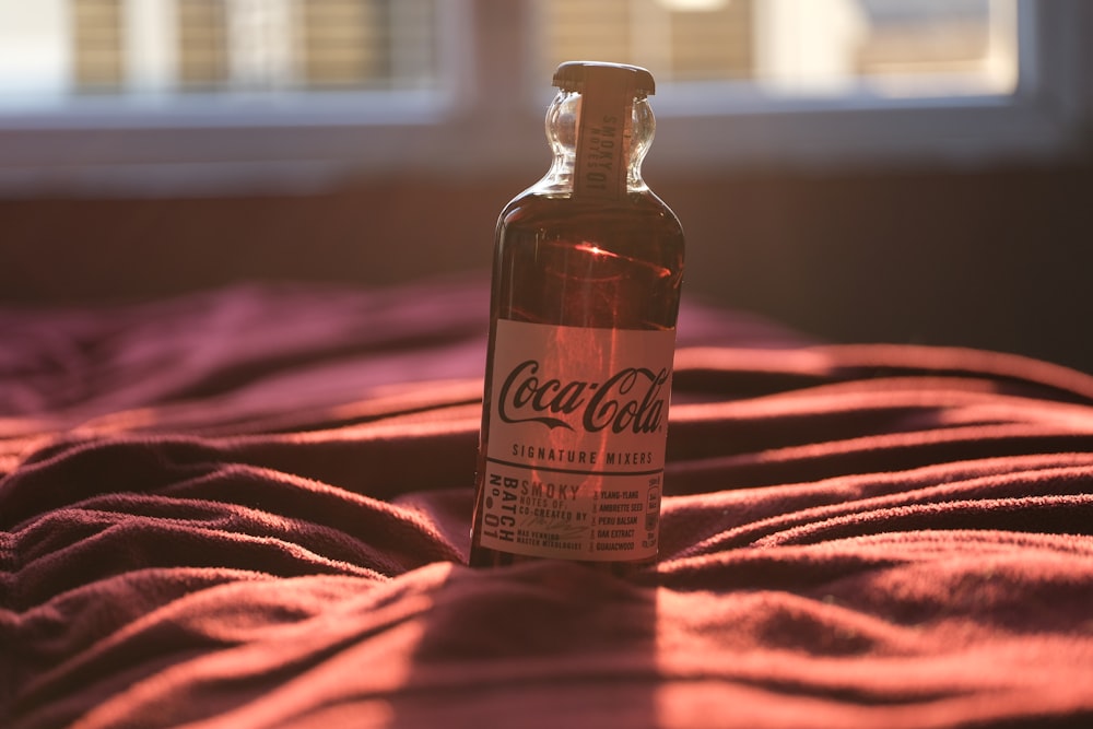 a bottle of coca cola sitting on top of a bed