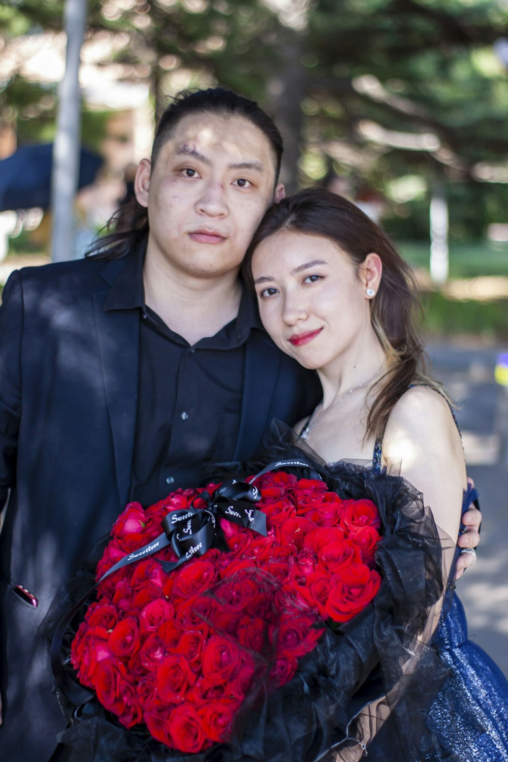 woman in black sleeveless dress holding red bouquet of flowers