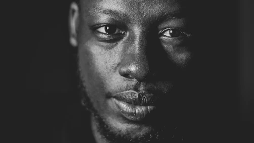 A striking black and white close-up portrait highlighting deep shadows and contrasts.