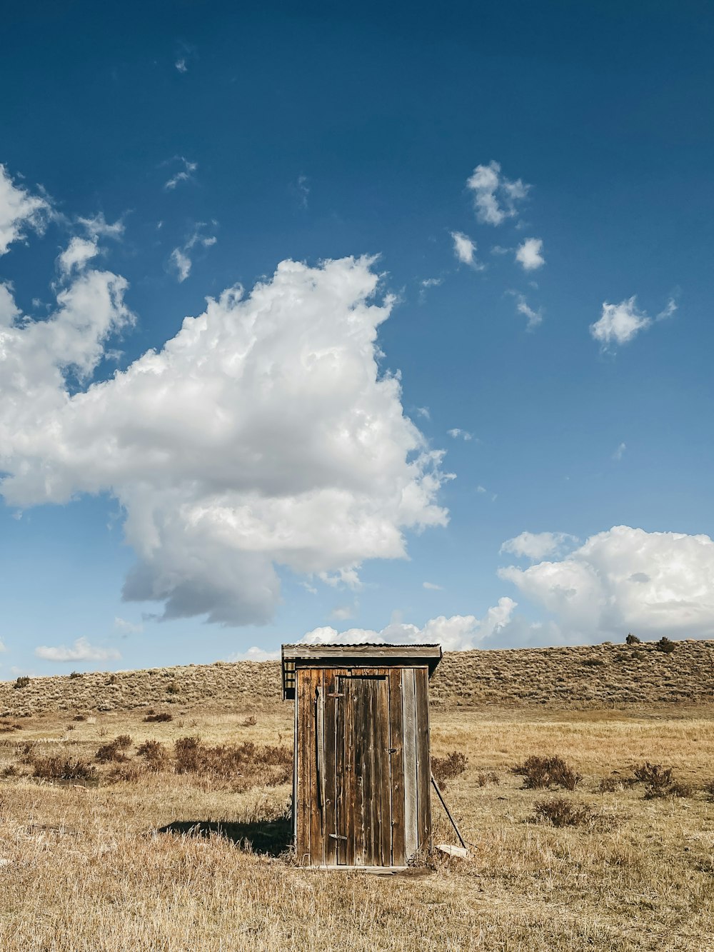 brown wooden post on brown field under blue and white cloudy sky during daytime