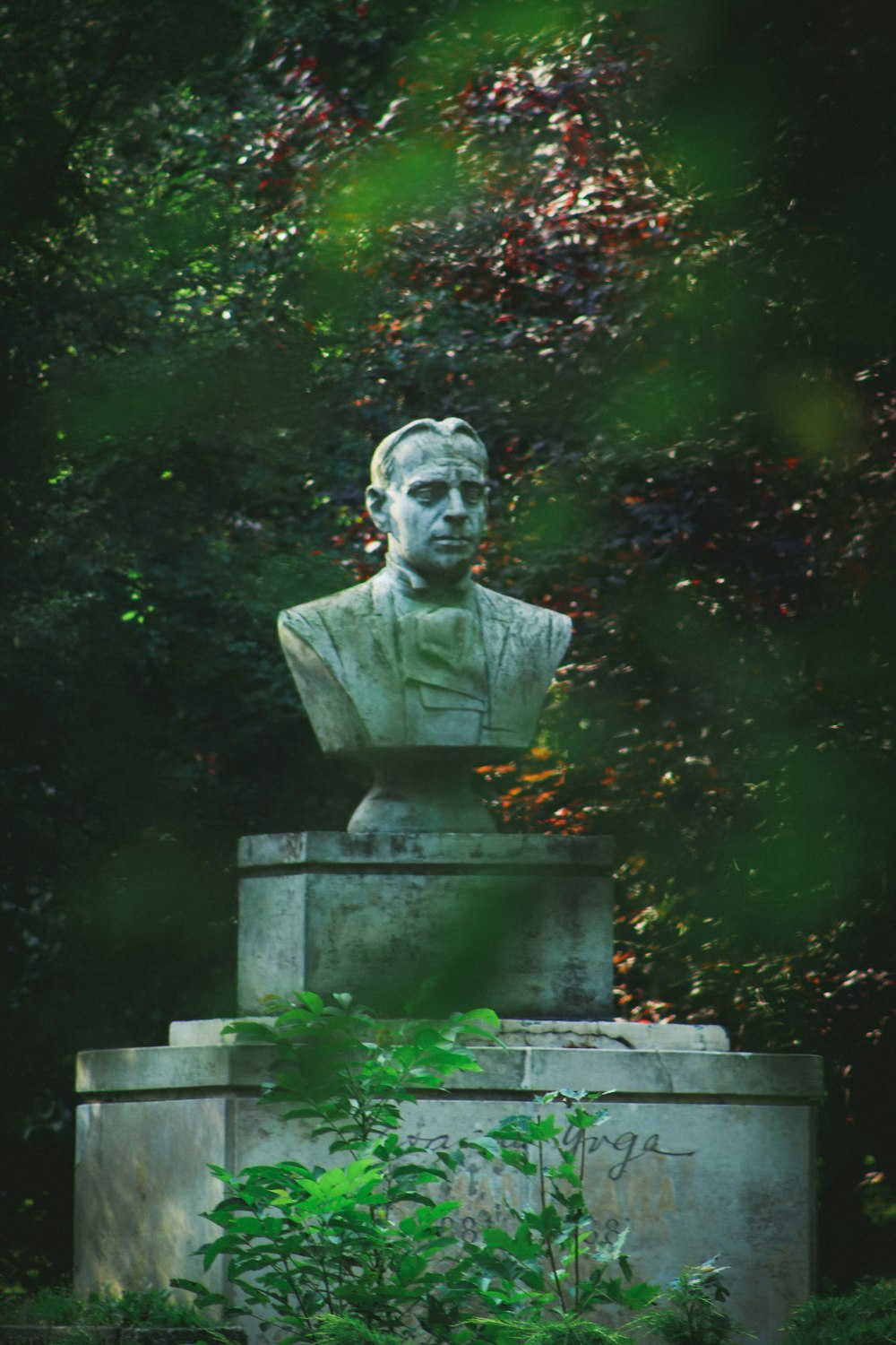 gray concrete statue near green plants during daytime