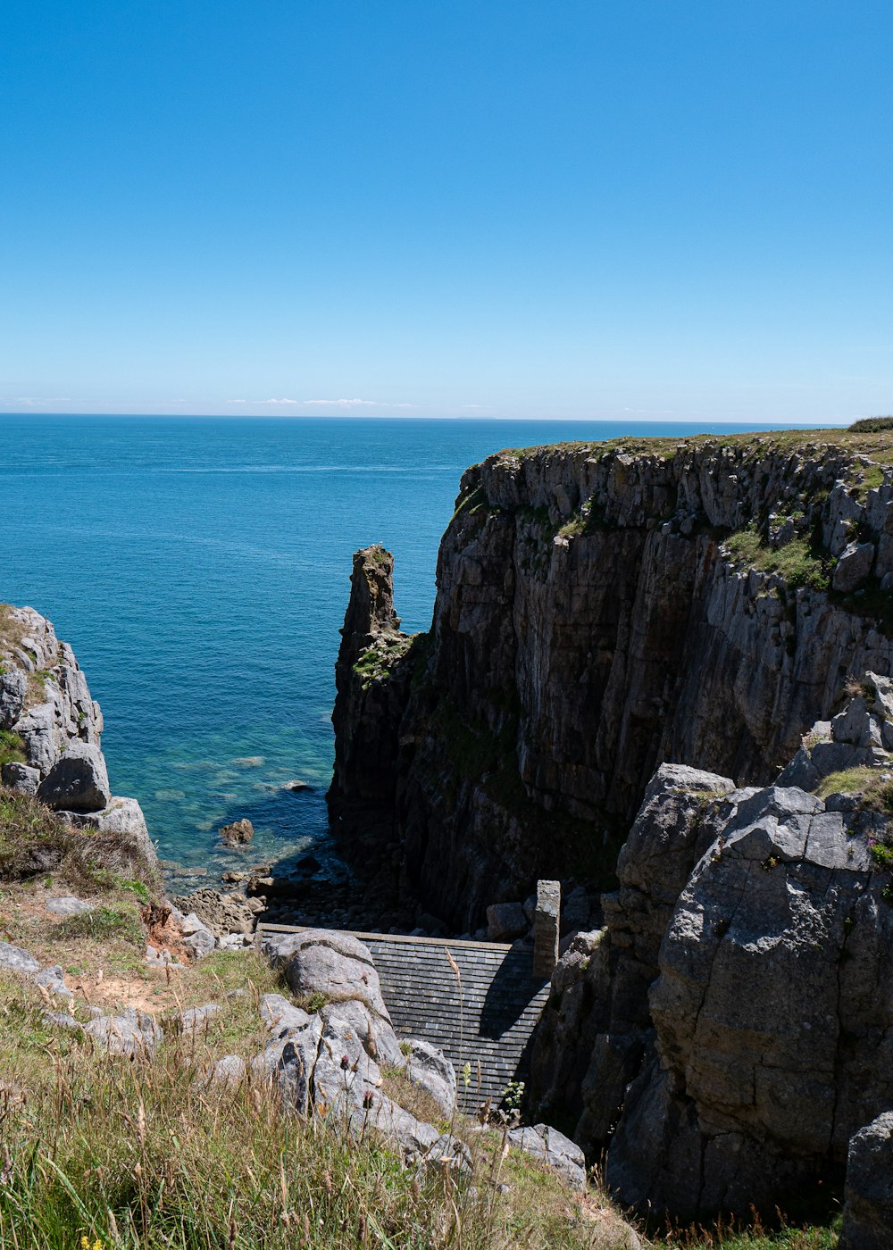 Formación rocosa marrón junto al mar azul bajo el cielo azul durante el día
