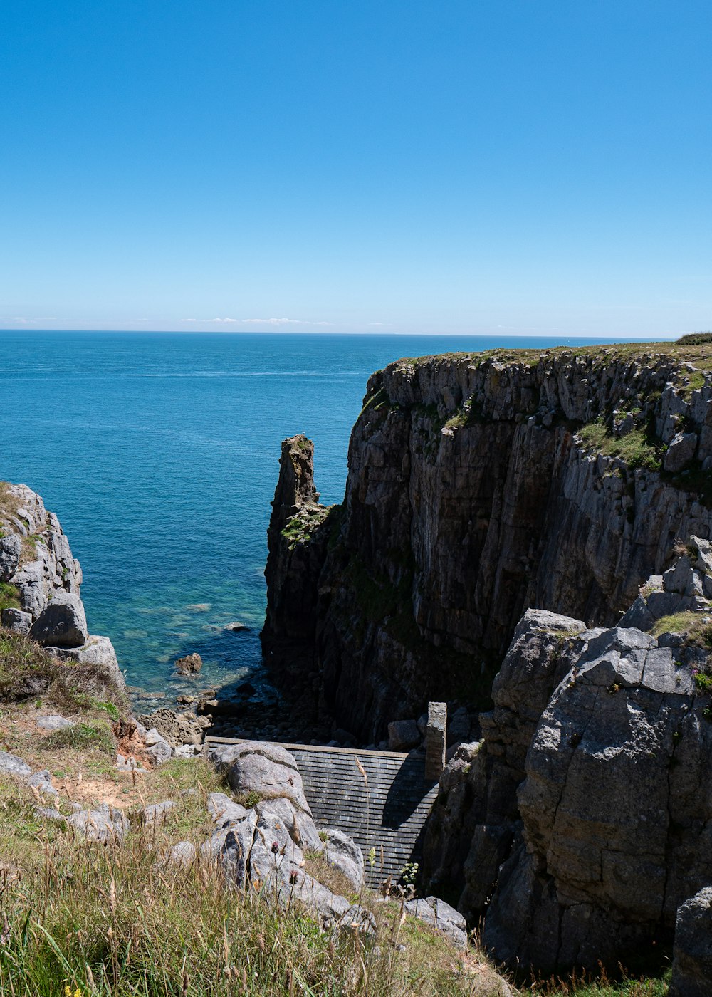 brown rock formation beside blue sea under blue sky during daytime