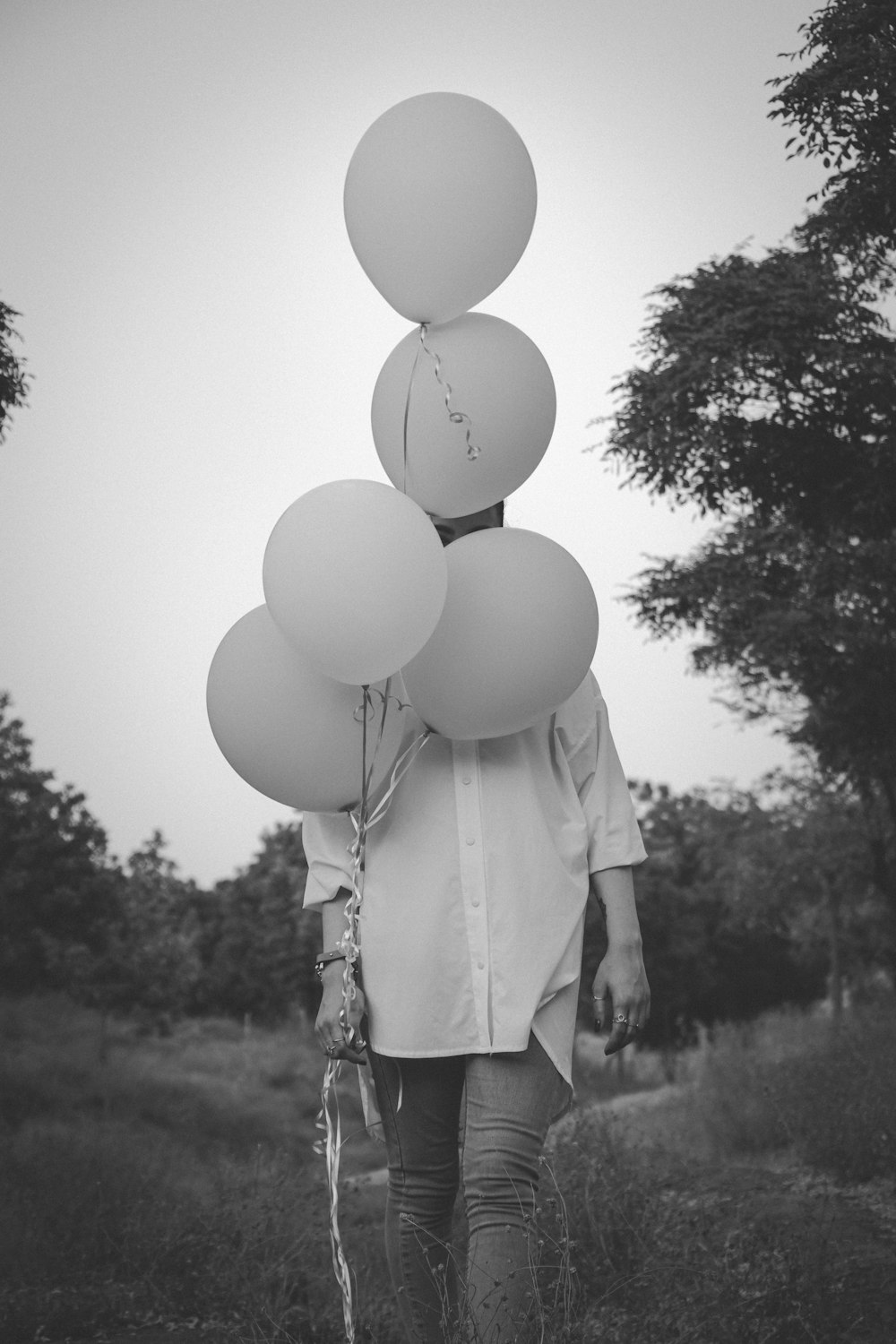 woman in white long sleeve shirt holding white balloons