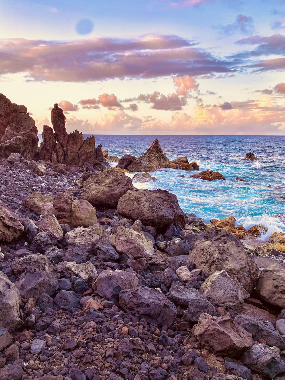rocky shore with ocean waves crashing on shore during sunset