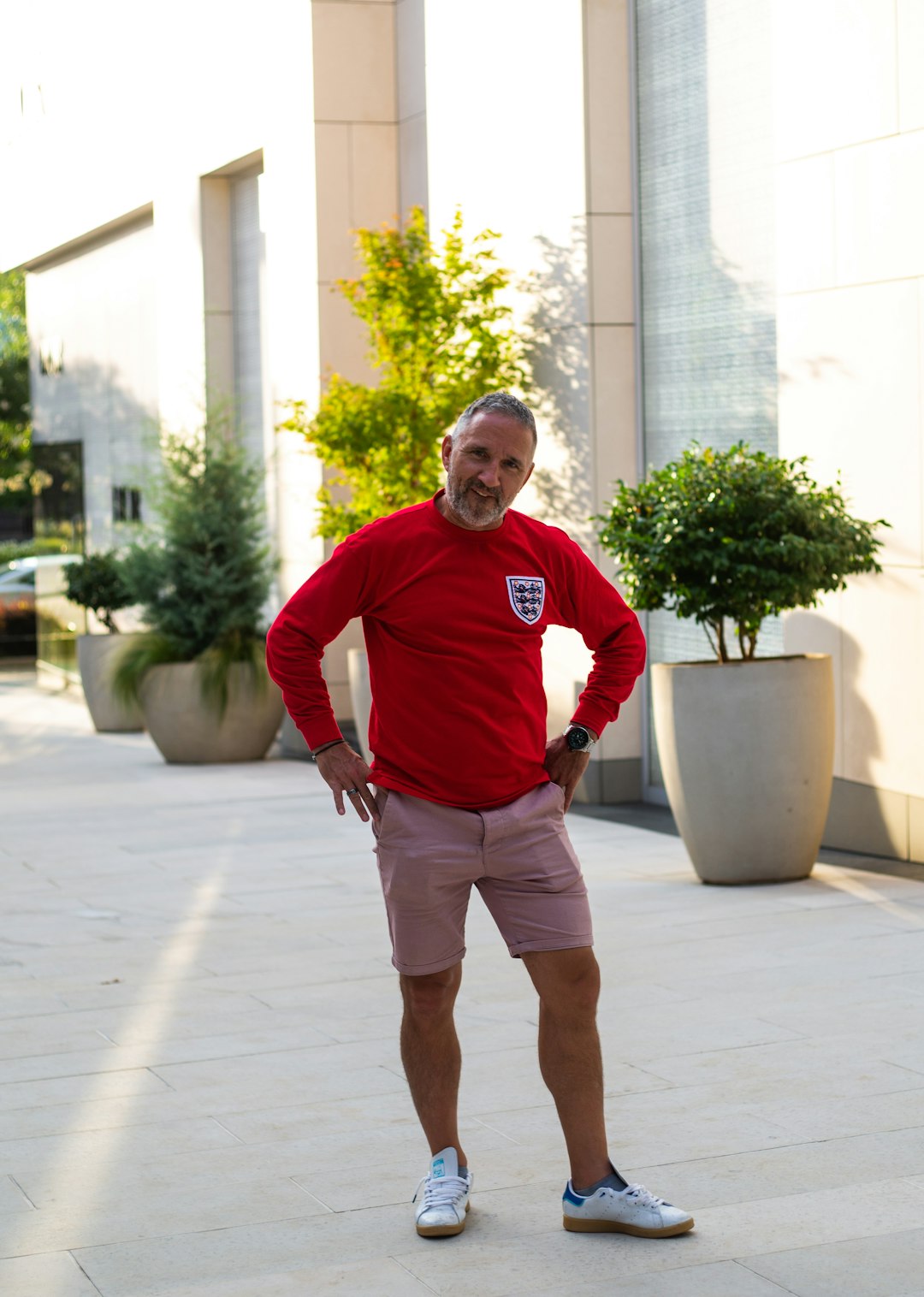 man in red sweater and gray shorts standing on gray concrete floor during daytime