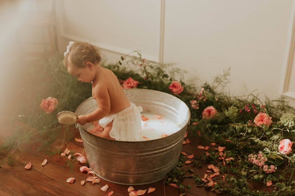 topless child sitting on white plastic bucket