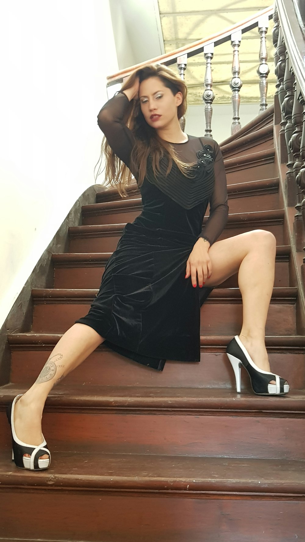 woman in black dress sitting on brown wooden stairs