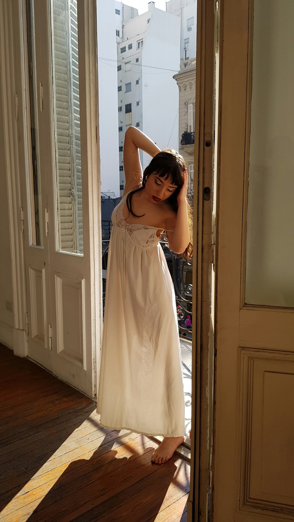 woman in beige sleeveless dress standing beside white wooden door