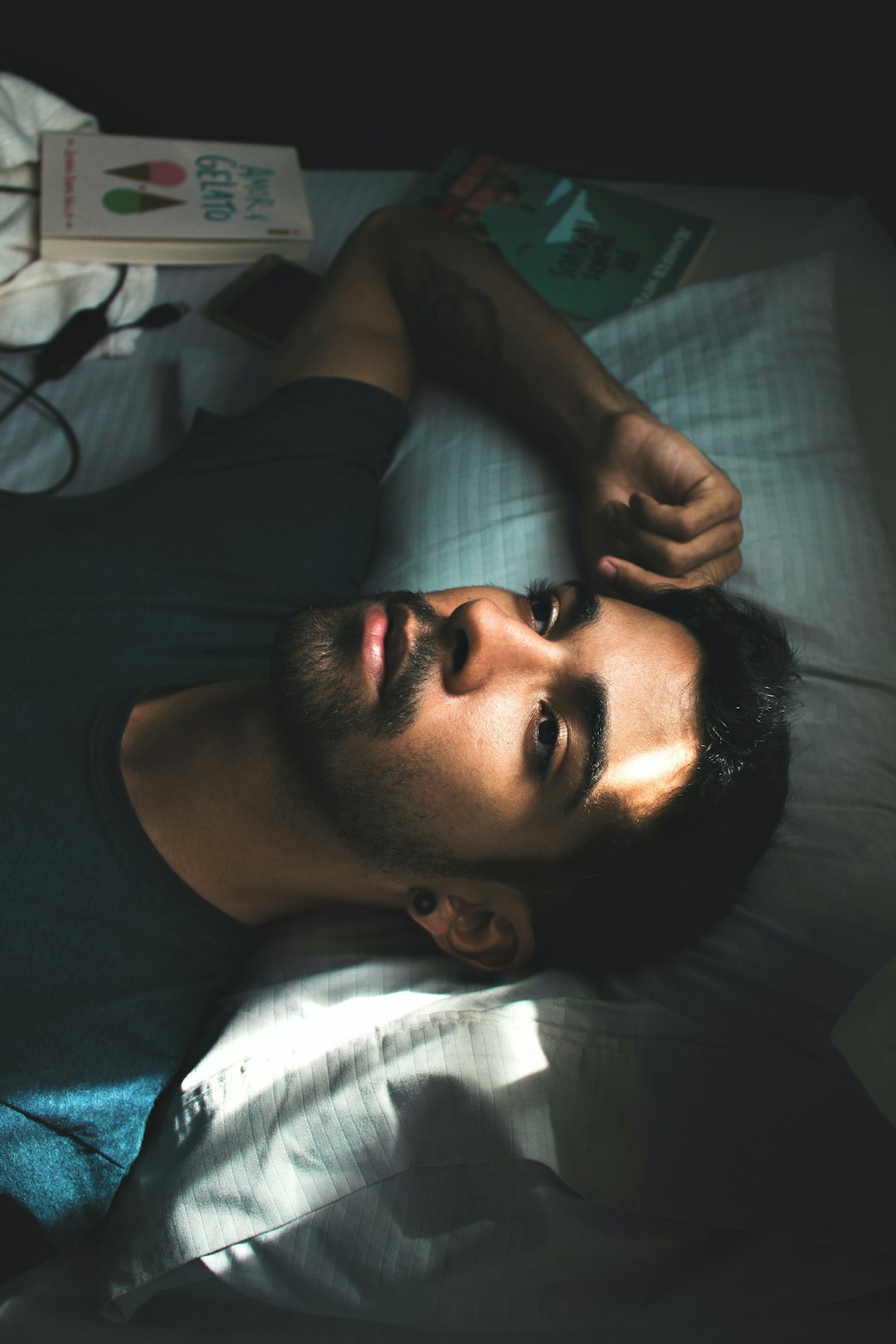 man in black crew neck shirt lying on bed