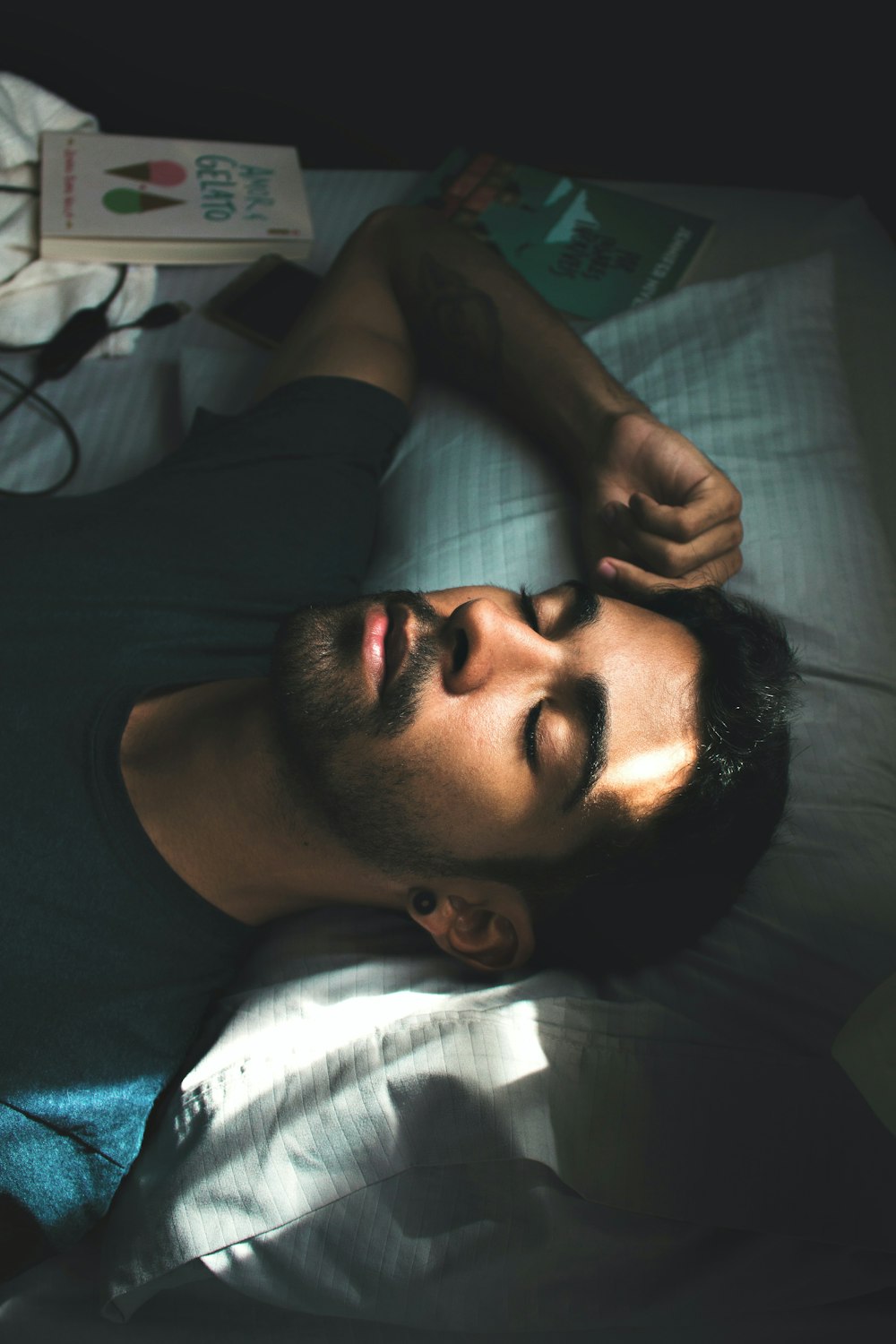 hombre con camiseta negra de cuello redondo acostado en la cama
