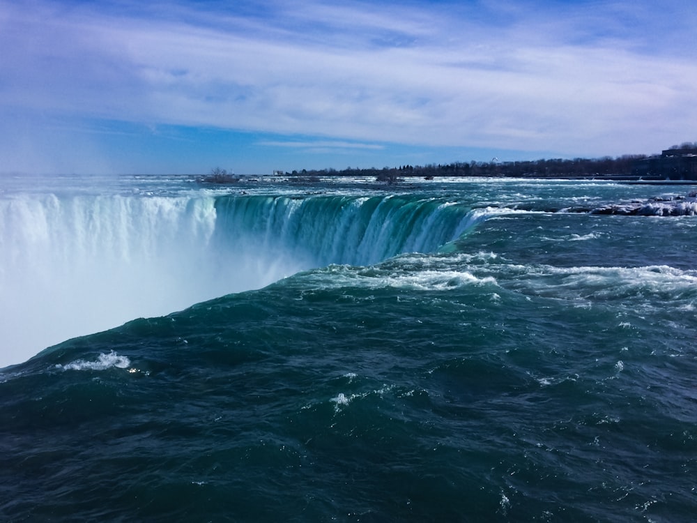 water falls under blue sky during daytime