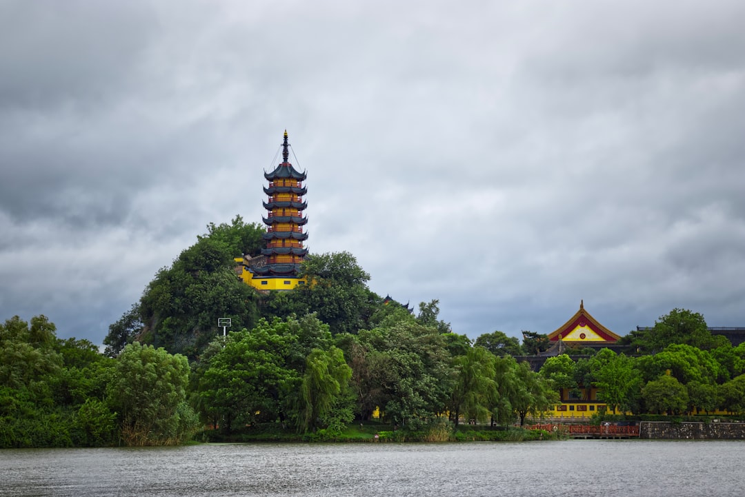 green trees near brown and yellow building under cloudy sky during daytime