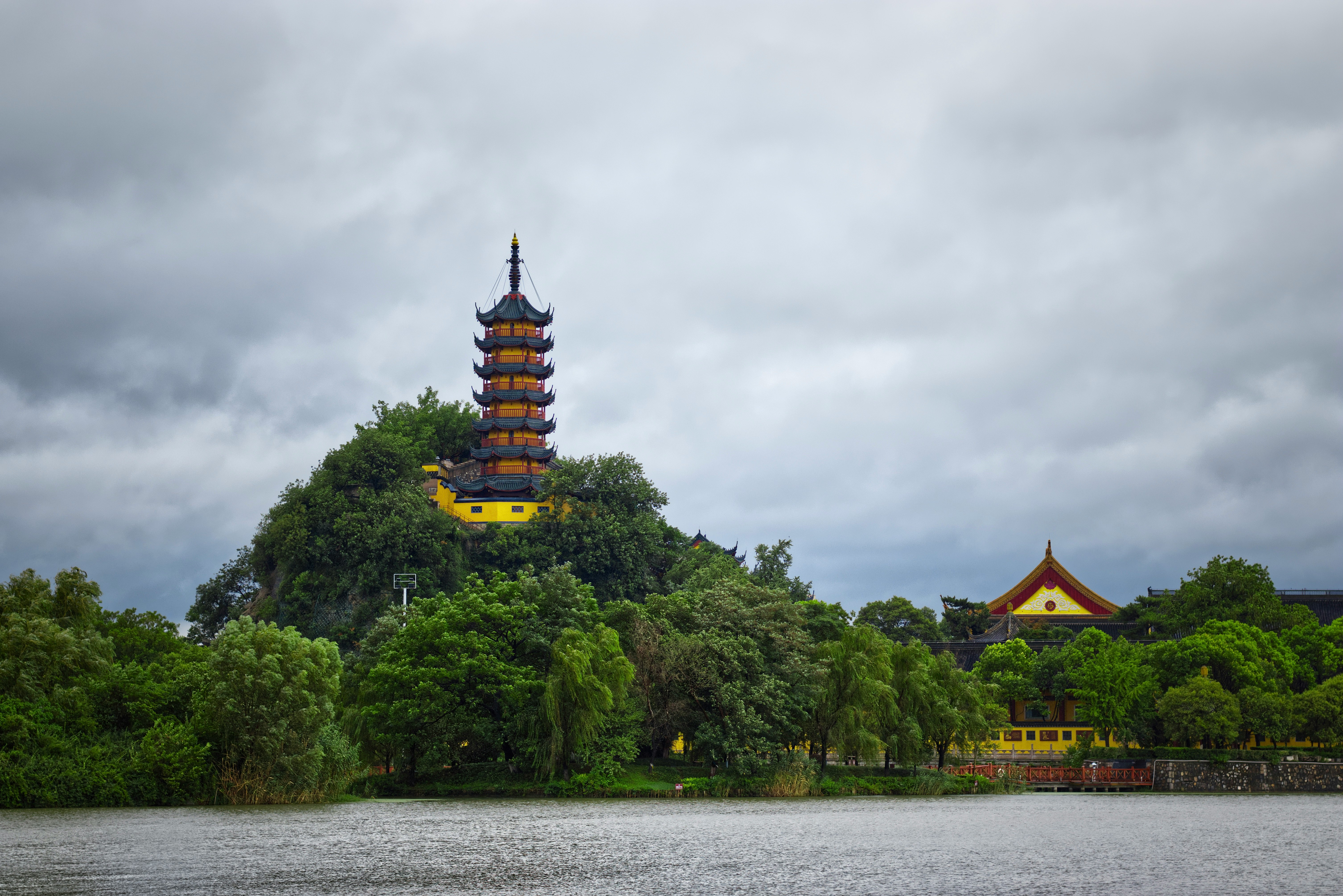 green trees near brown and yellow building under cloudy sky during daytime