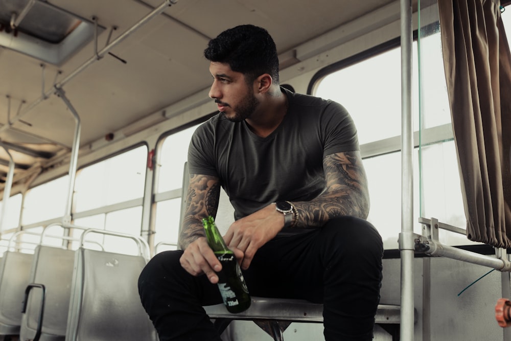 man in black long sleeve shirt holding green glass bottle