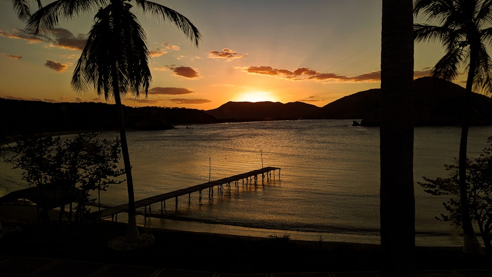 brown wooden dock on sea during sunset