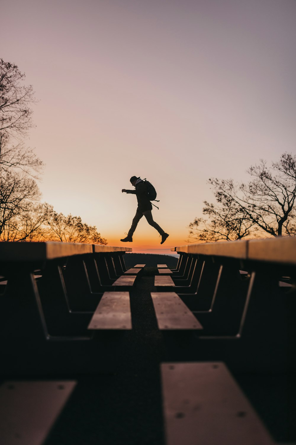 man in black jacket and pants standing on concrete bench during daytime