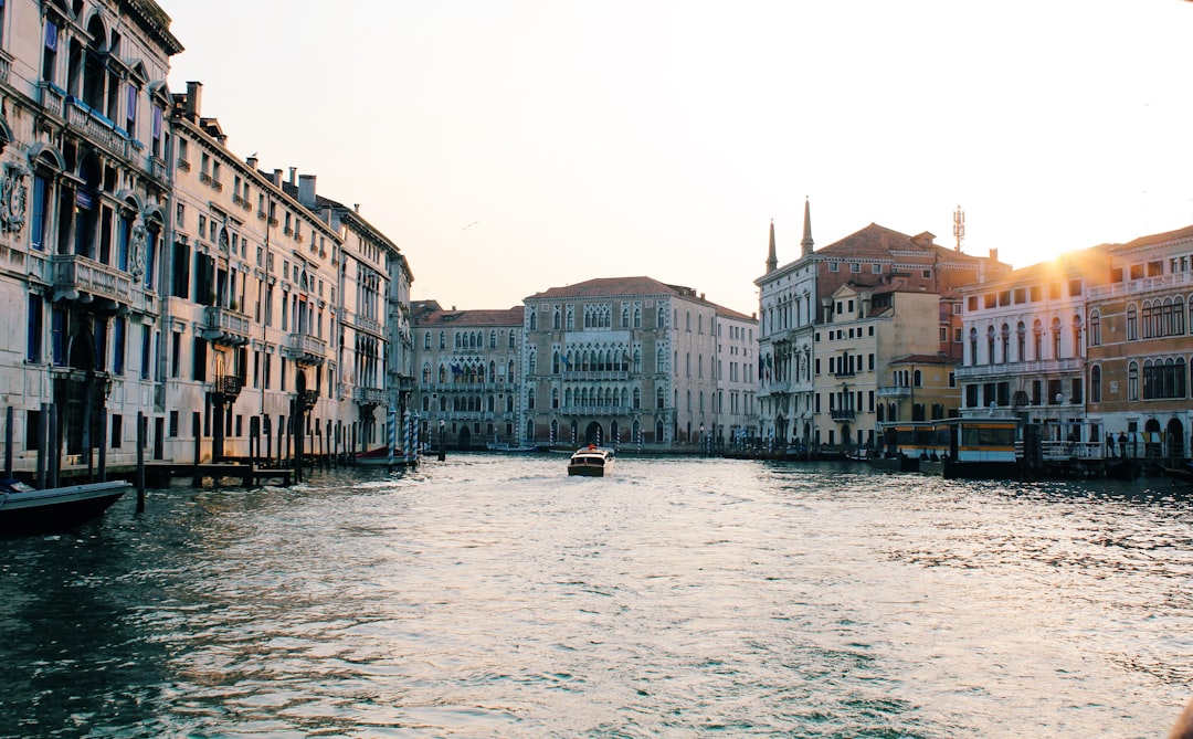 people on boat on river between buildings during daytime