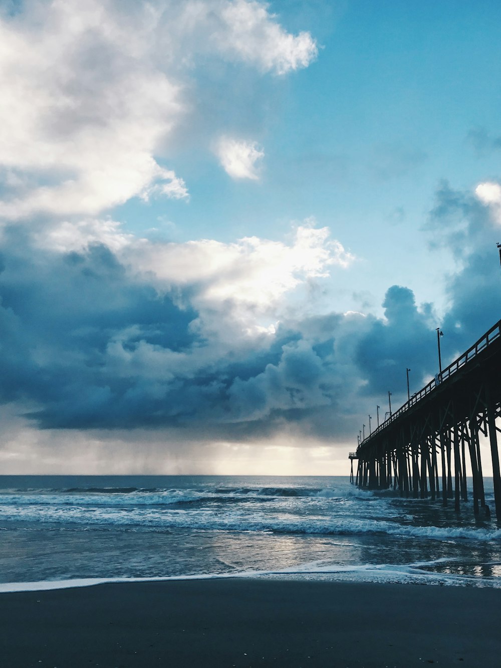 muelle marino bajo cielo azul y nubes blancas durante el día