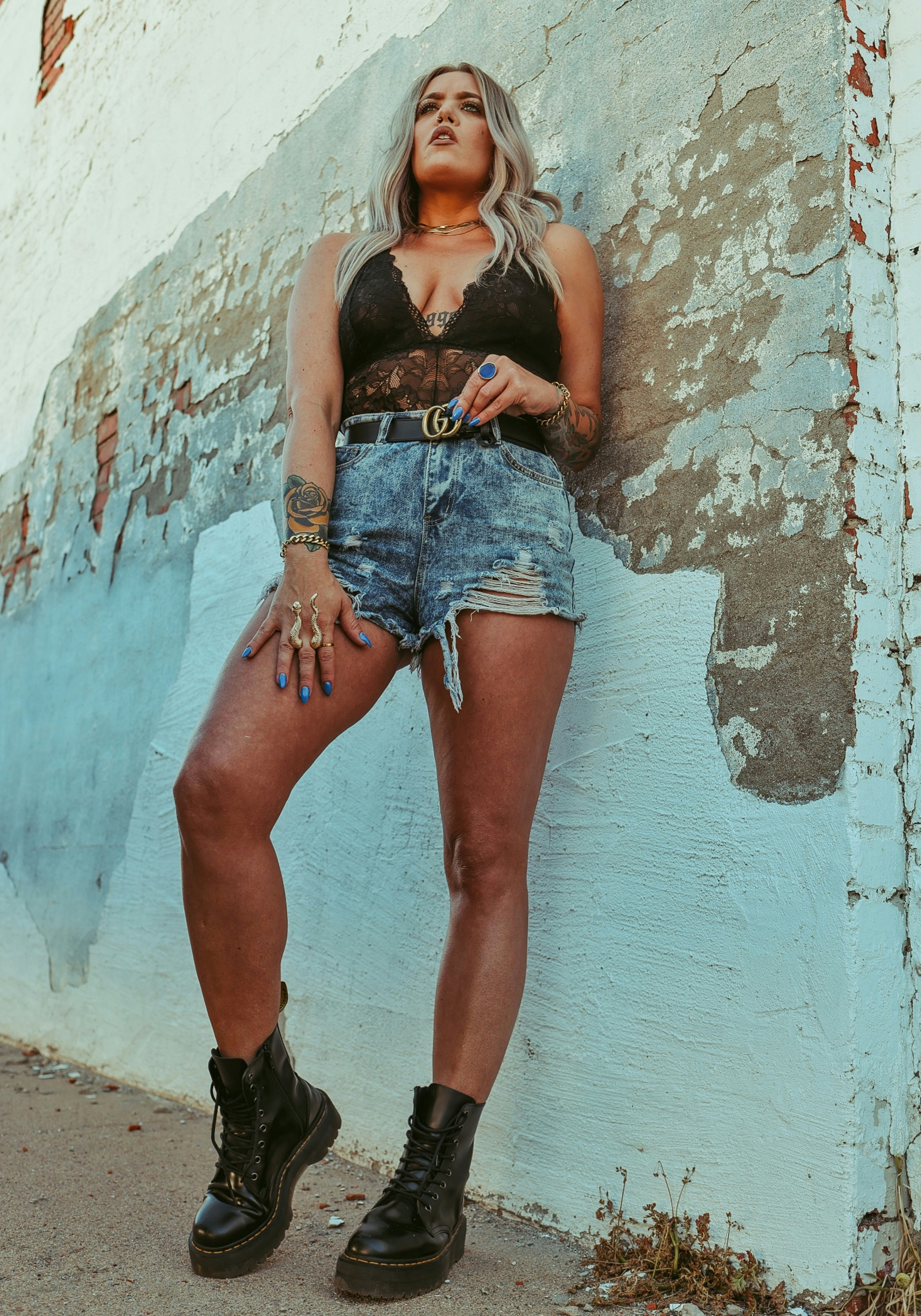 woman in blue denim shorts leaning on wall