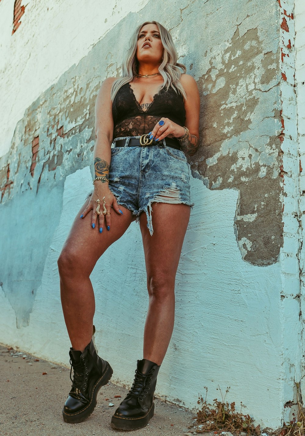 woman in blue denim shorts leaning on wall