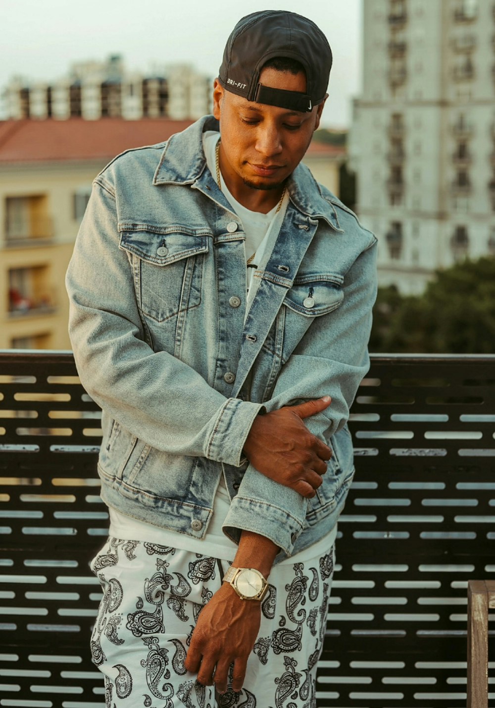 man in blue denim button up jacket sitting on black metal bench during daytime