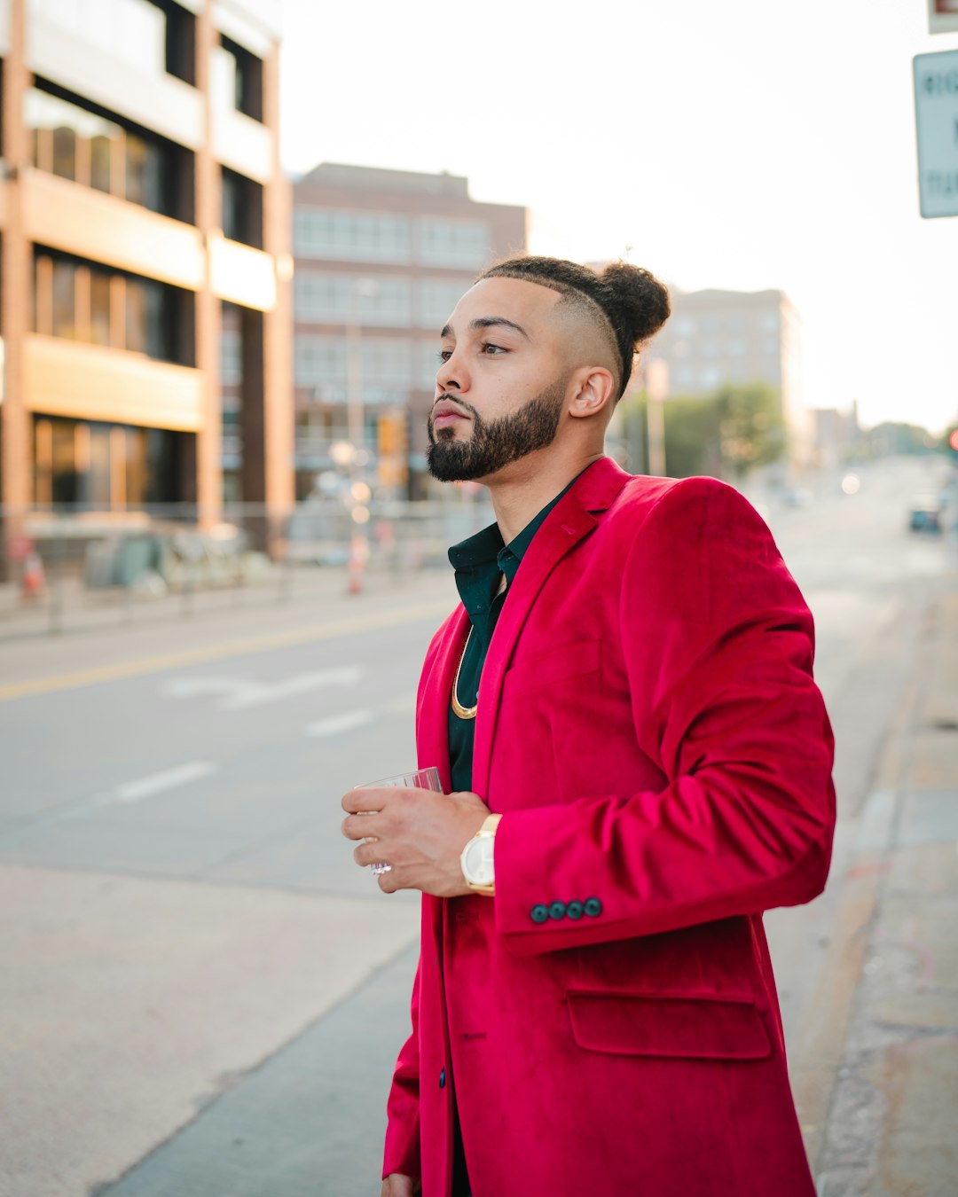 man in red coat standing on road during daytime