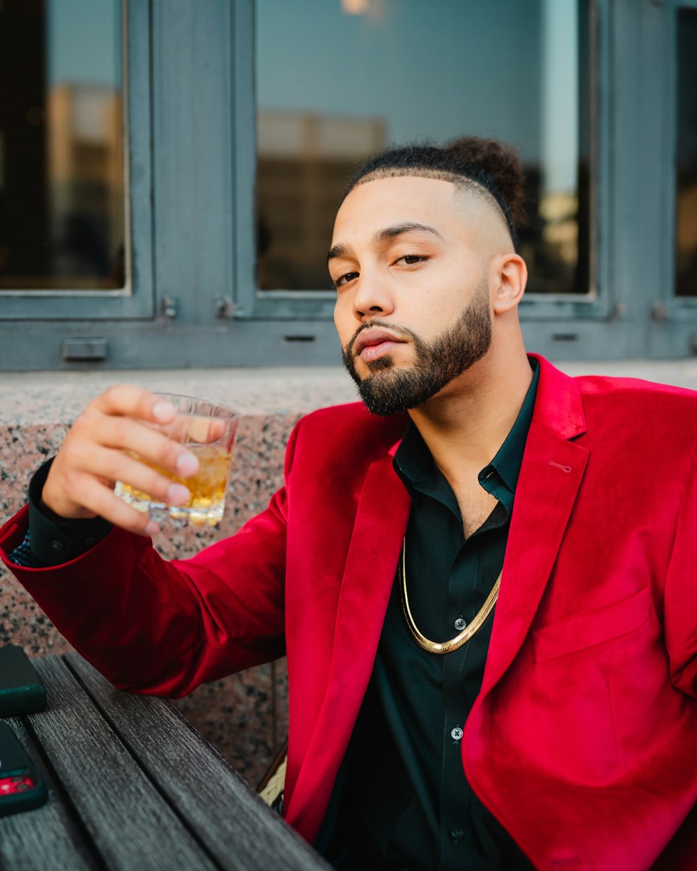 homme en blazer rouge tenant un verre à boire transparent