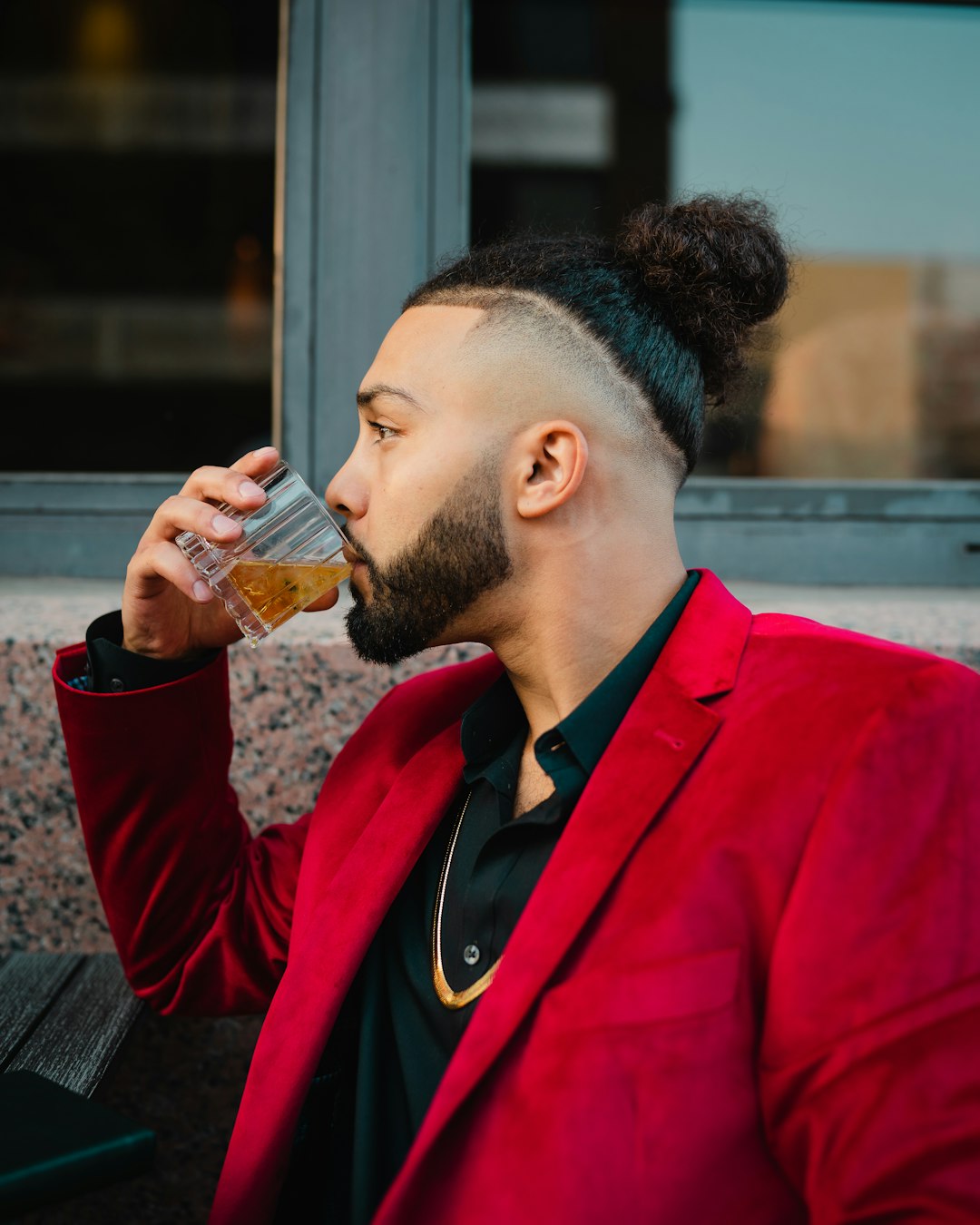 man in red blazer drinking from clear drinking glass