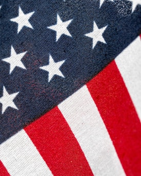 A close-up view of a section of the American flag, featuring a pattern of white stars against a blue background and red and white stripes.