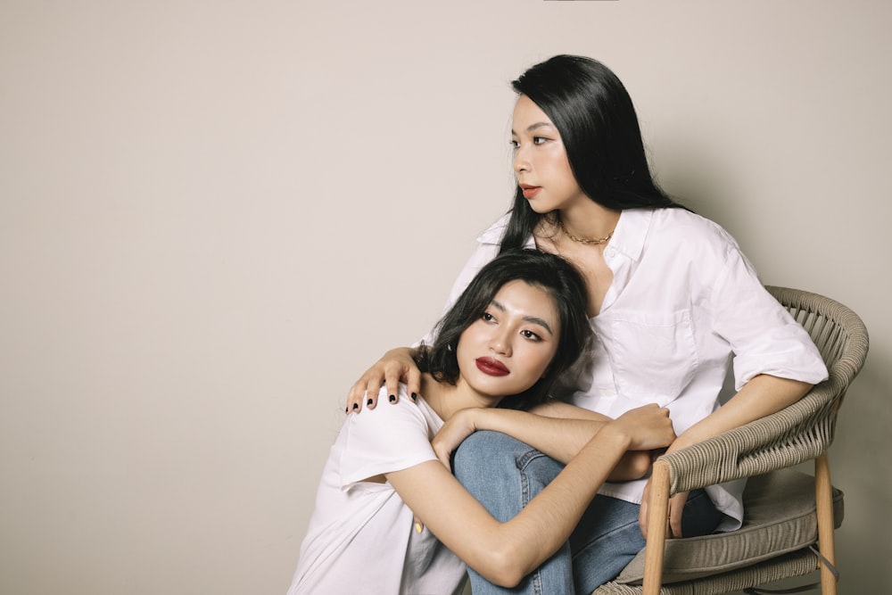 2 women sitting on brown wooden chair