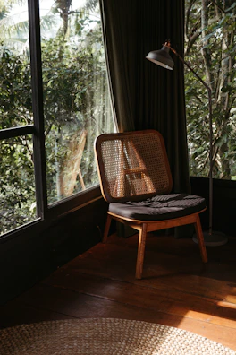 A cozy living room corner featuring a metal wall sconce casting soft light over a woven rattan chair.