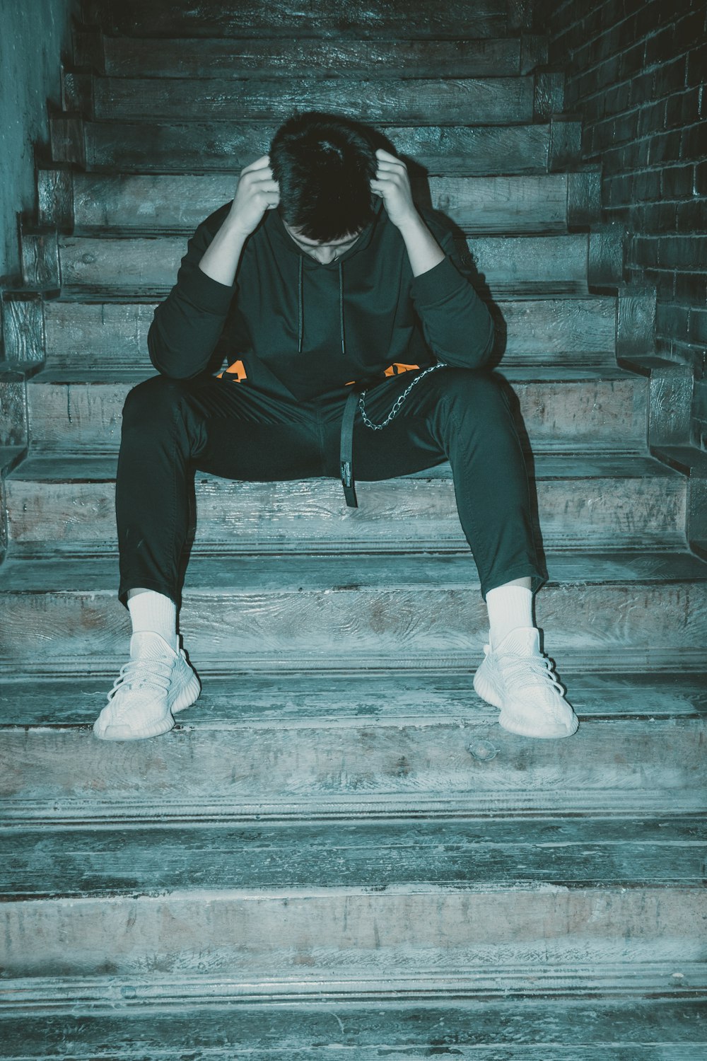 man in black hoodie and black pants sitting on stairs