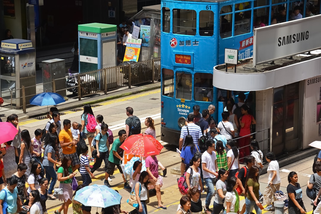 people in a street with a red and green bus during daytime