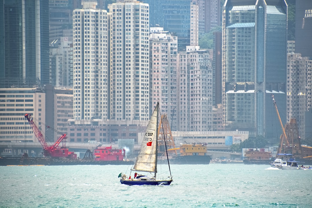 white and red sail boat on sea near city buildings during daytime