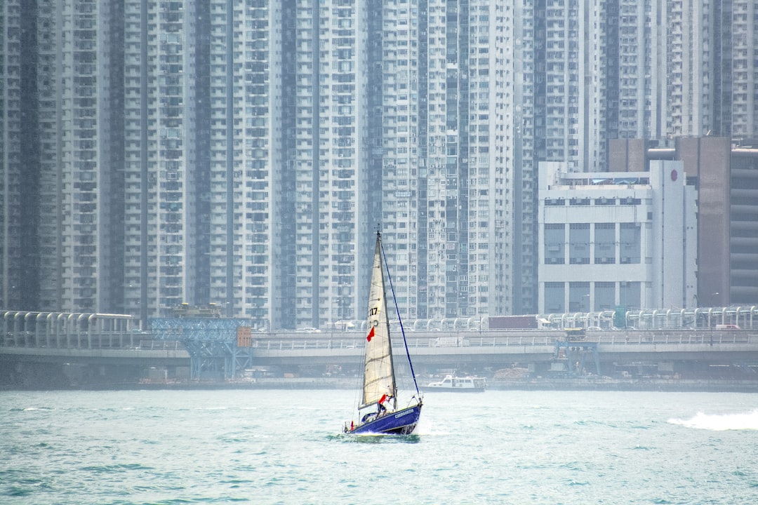 white and blue boat on sea near high rise buildings during daytime