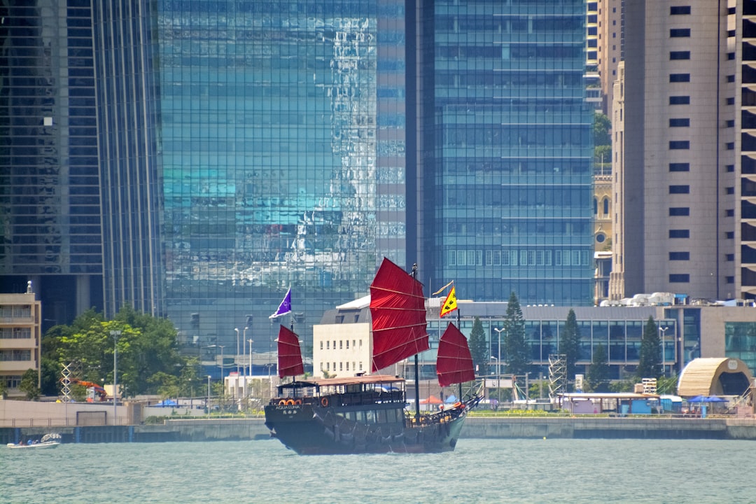 red sail boat on water near city buildings during daytime