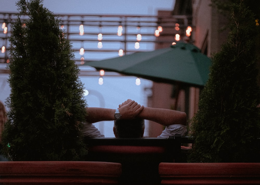 Persona in camicia grigia a maniche lunghe seduta sulla panchina rossa