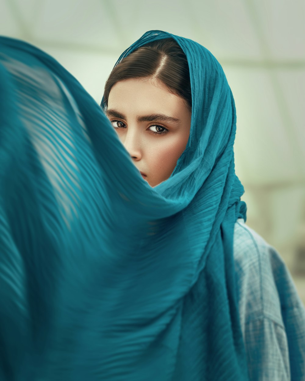 Femme en hijab bleu couvrant son visage avec un textile bleu