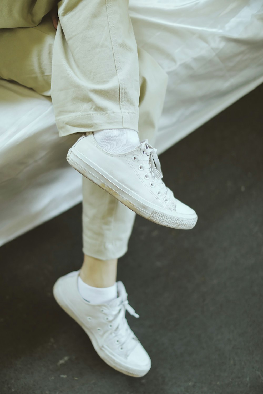 person in white pants and white nike sneakers