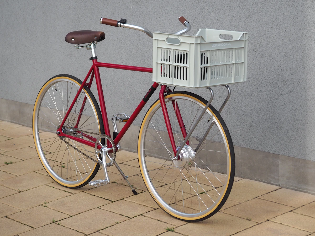 Red and white city bike parked beside a white plastic crate