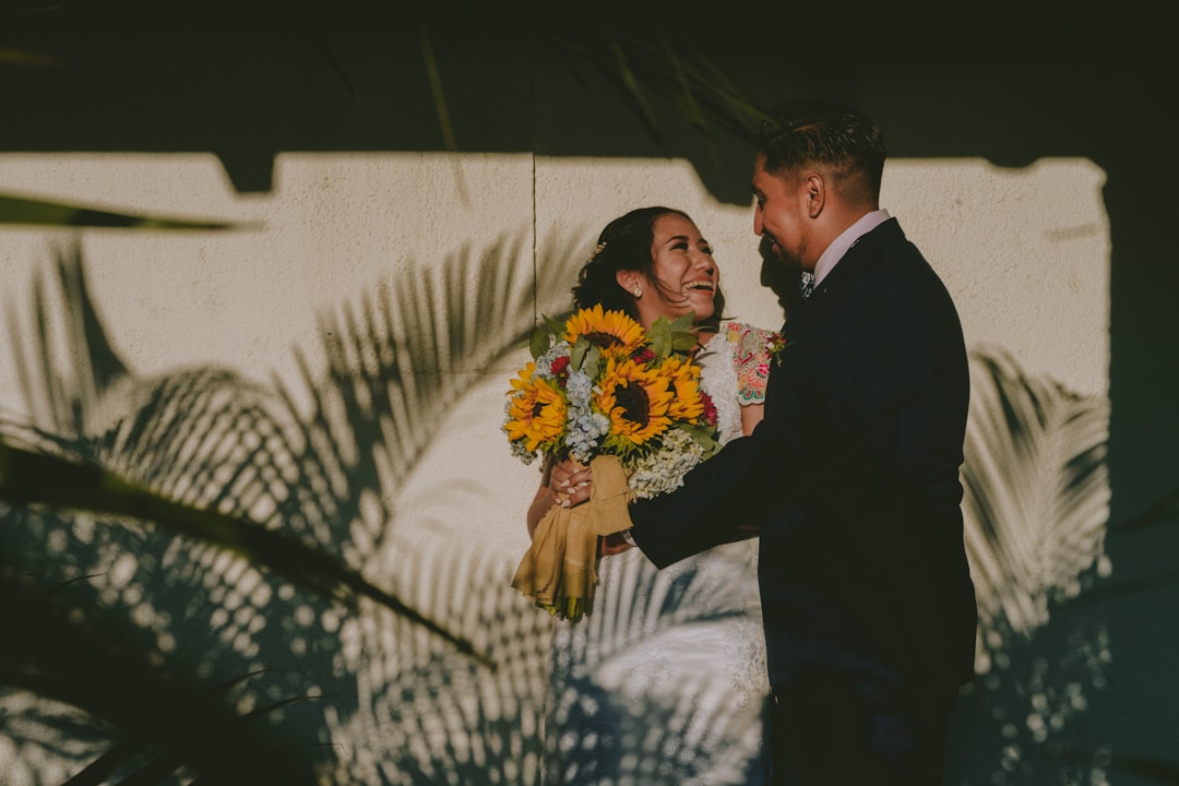 man in black suit jacket holding woman in white and blue floral dress