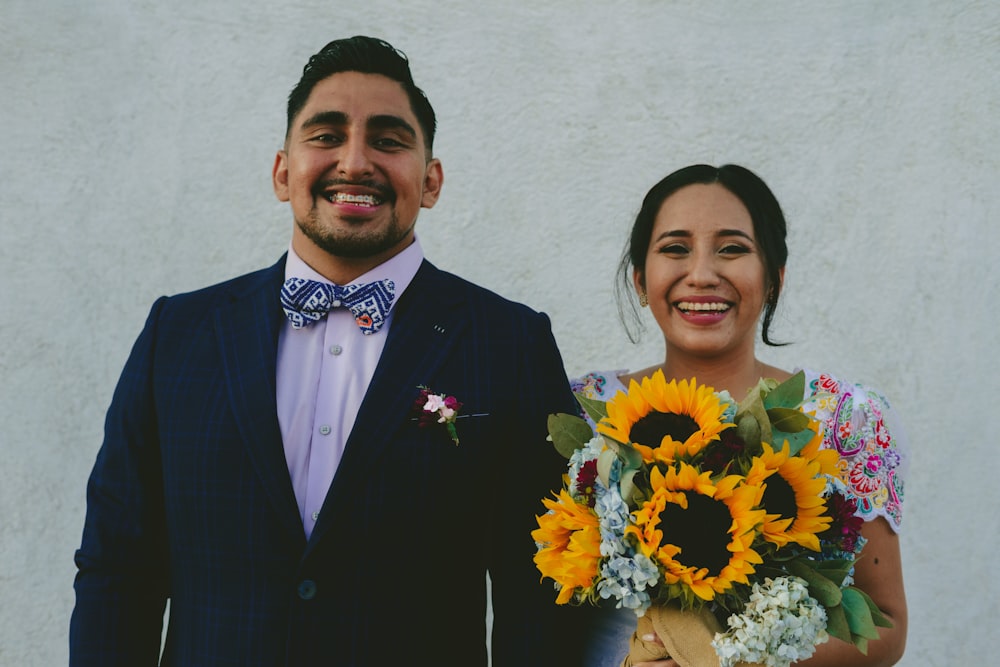 man in black suit standing beside woman in yellow and red floral dress