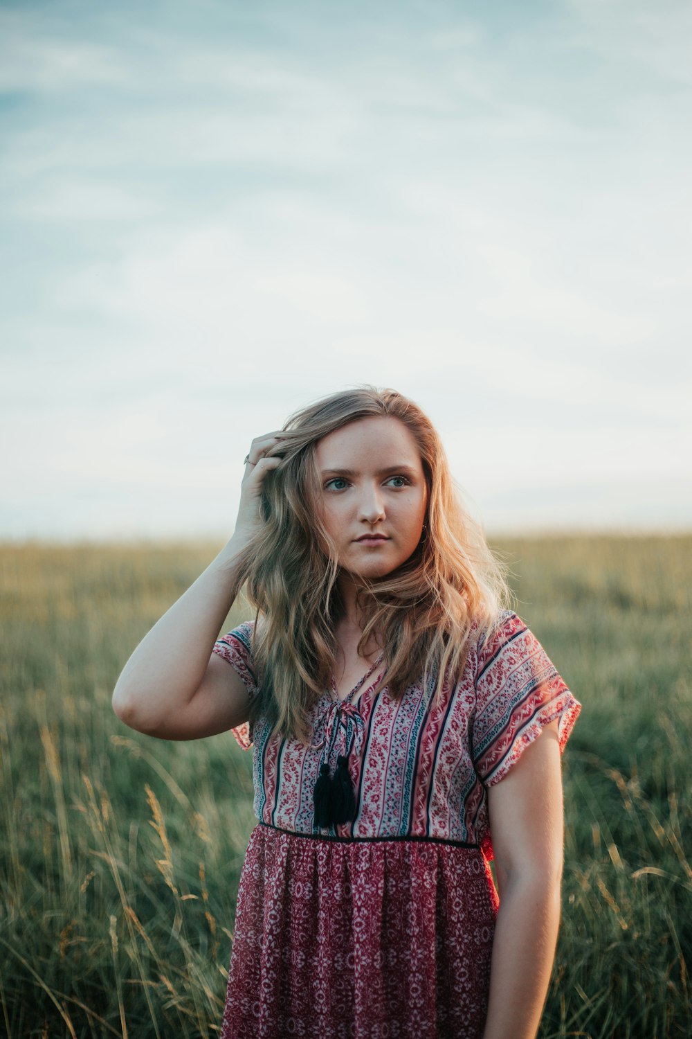 woman in red and black sleeveless dress standing on green grass field during daytime