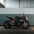black and red sports bike parked beside white wall