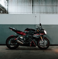 black and red sports bike parked beside white wall